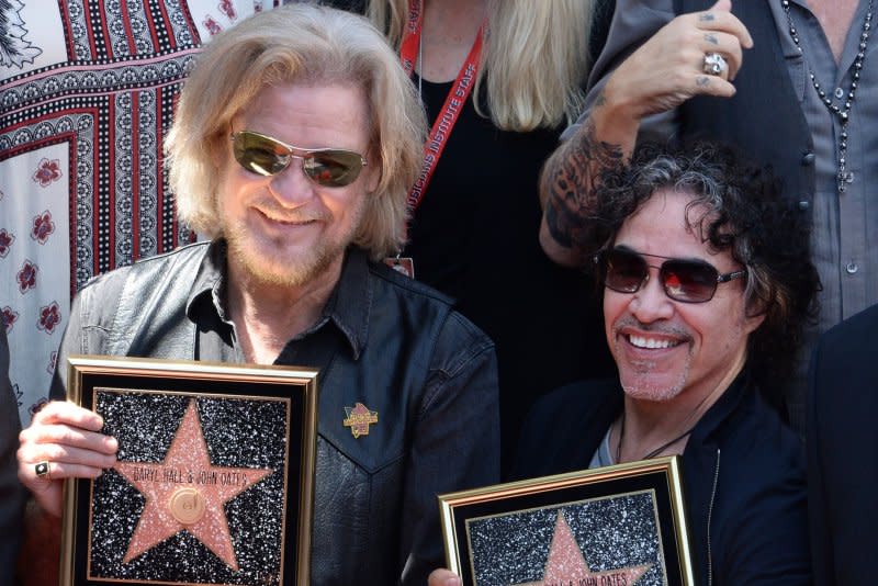 Daryl Hall (L) and John Oates hold replica plaques during an unveiling ceremony honoring the singing duo with the 2,587th star on the Hollywood Walk of Fame in Los Angeles in 2016. Oates was eliminated from "The Masked Singer" Wednesday night. File Photo by Jim Ruymen/UPI