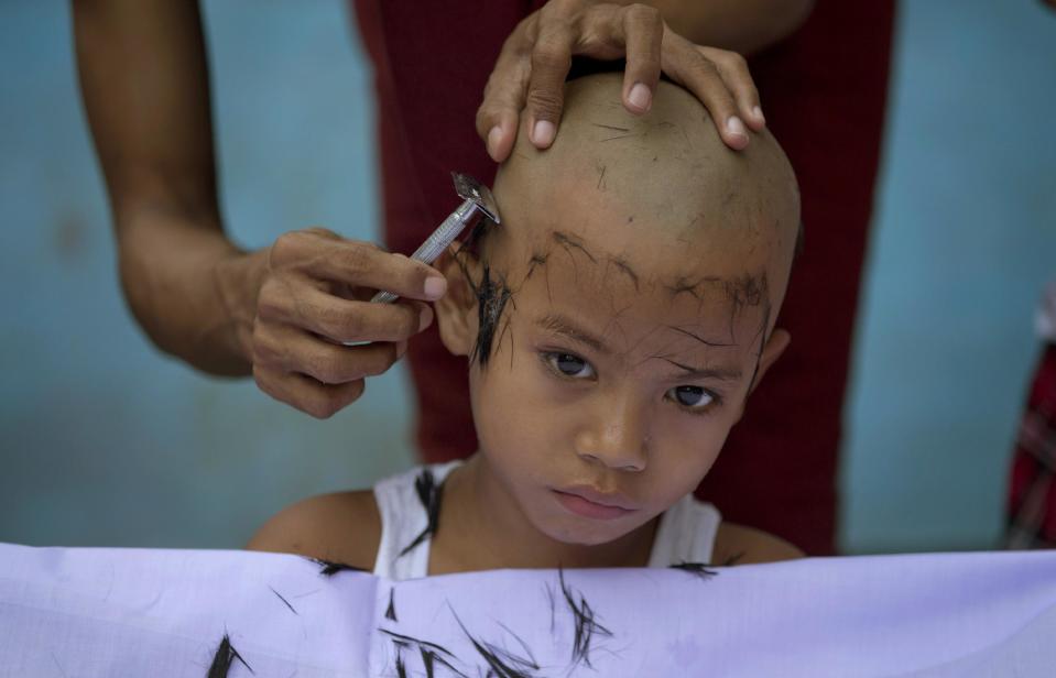 In this April 8, 2014 photo, a Buddhist monk shaves the head of a boy during an ordaining ceremony at a Buddhist monastery in suburbs of Yangon, Myanmar. Though most boys only remain monks for a few days, ordination is seen as a right of passage in this predominantly Buddhist nation of 60 million. (AP Photo/Gemunu Amarasinghe)