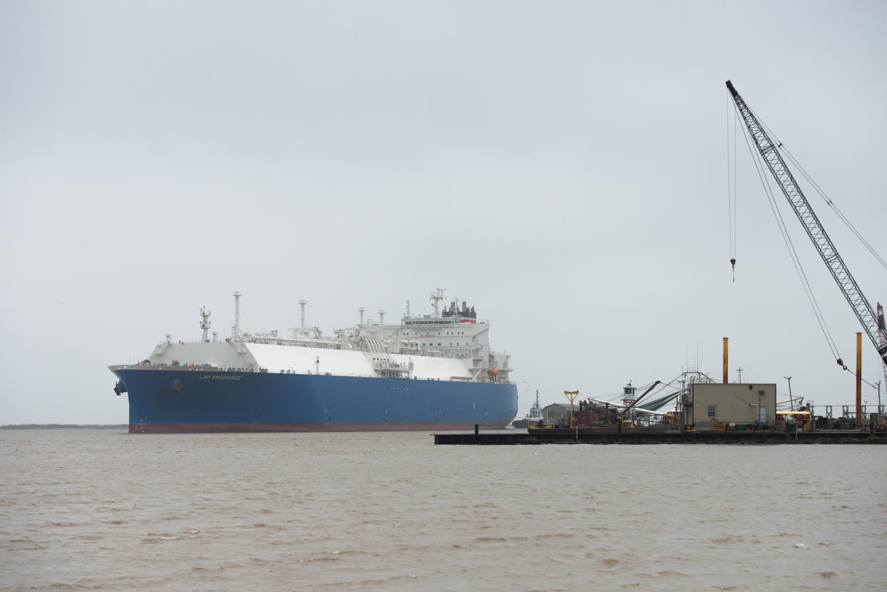 An LNG tanker passes a floating rig.