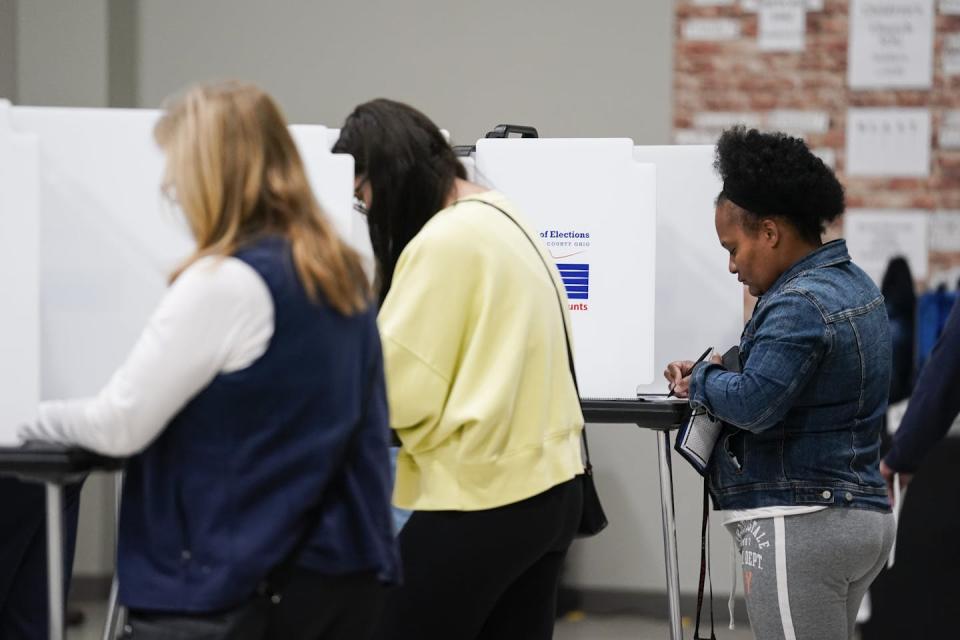 Three women standing at voting booths.