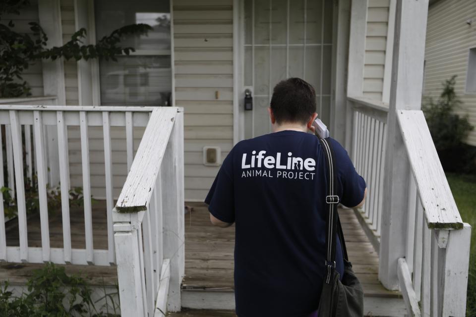 In this Tuesday, Aug. 27, 2019 photo, Lizzy Trawick conducts door-to-door outreach for LifeLine Animal Project's Pets for Life program in Atlanta. The program provides free pet health services, supplies and food to help owners in need. (AP Photo/Andrea Smith)