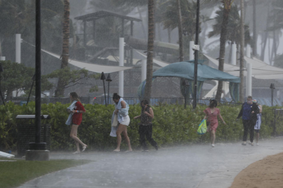 People scramble to get out of the heavy rain on Waikiki Beach, Monday, Dec. 6, 2021, in Honolulu. (AP Photo/Marco Garcia)