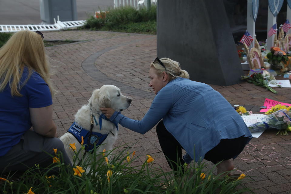 A woman kneels down to pet Emma, one of LCC’s comfort dogs.
