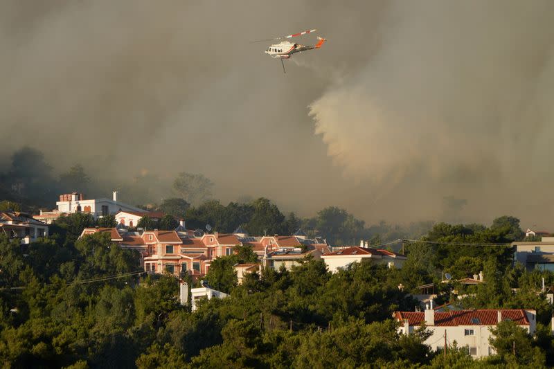 Firefighting helicopter makes a water drop, as a wildfire burns in Ntrafi, near Athens