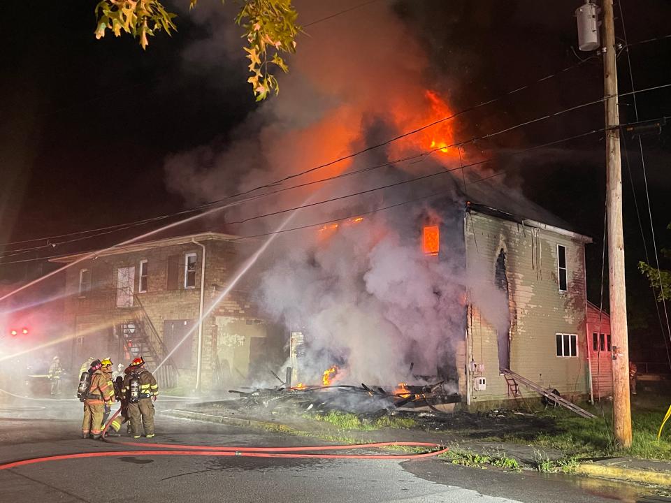 Flames break through the roof of this home along River Street in Benson Borough as fire crews work from the outside to put out the fire.