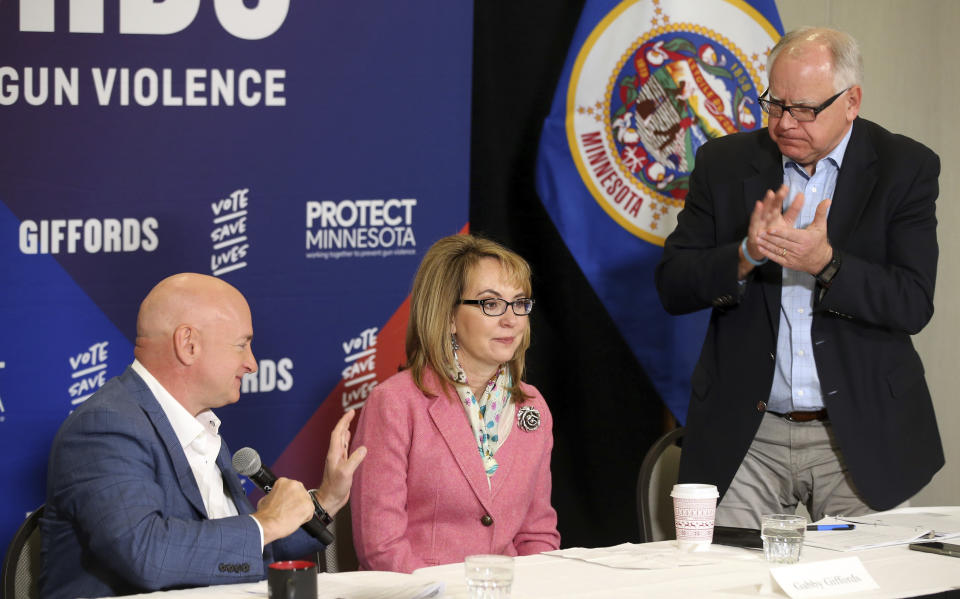 In this Oct. 26, 2018 photo, Minnesota gubernatorial candidate, Democrat Tim Walz, right, applauds as Capt. Mark Kelly, left, introduces his wife, former Rep. Gabby Giffords as they hosted a roundtable against gun violence in Minneapolis. The 2018 election marks the first time that groups supporting gun control measures could spend more on a campaign than the National Rifle Association. (AP Photo/Jim Mone)