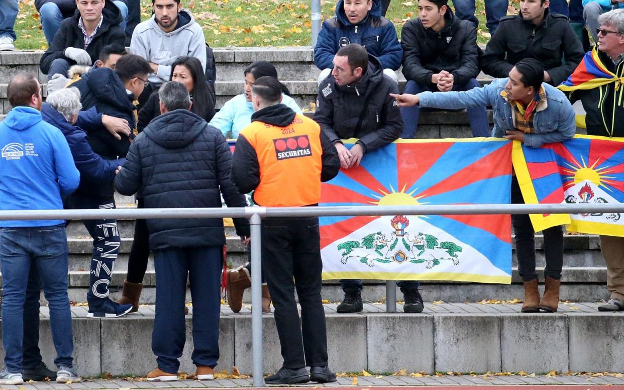 A Chinese spectator attempts to tear away a Tibetian flag which was raised by others in protest of China's politics regarding Tibet at the friendly match between TSV Schott Mainz and China's U20 team at the regional sports facility in Mainz, Germany, - dpa