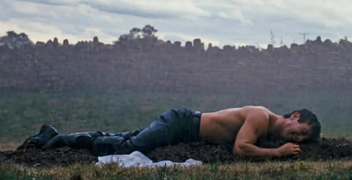 A man lays crying on a grave in Saltburn.