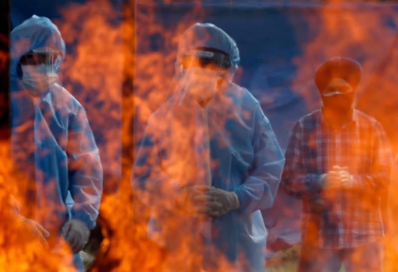 FILE PHOTO: Relatives stand next to the burning pyre of a man who died from the coronavirus disease (COVID-19) during his cremation at a crematorium ground in Srinagar