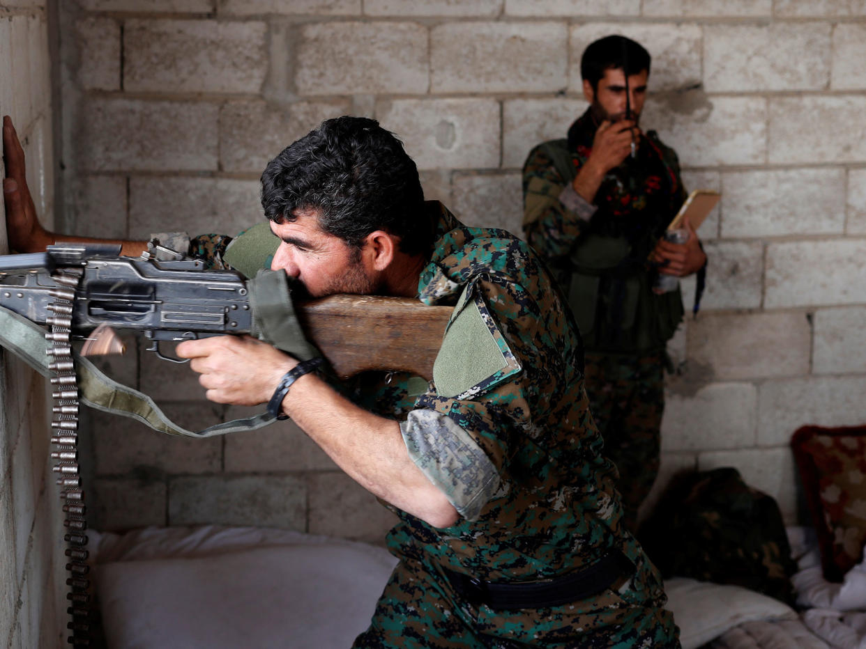 A Kurdish fighter from the People's Protection Units (YPG) fires his weapon from a house in Raqqa: Reuters