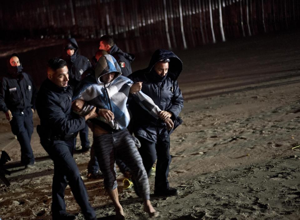Mexican police help a Honduran migrant who tried to cross the U.S. border by the sea in Tijuana beach, Mexico, Thursday, Nov. 29, 2018. Aid workers and humanitarian organizations expressed concerns Thursday about the unsanitary conditions at the sports complex in Tijuana where more than 6,000 Central American migrants are packed into a space adequate for half that many people and where lice infestations and respiratory infections are rampant. (AP Photo/Ramon Espinosa)