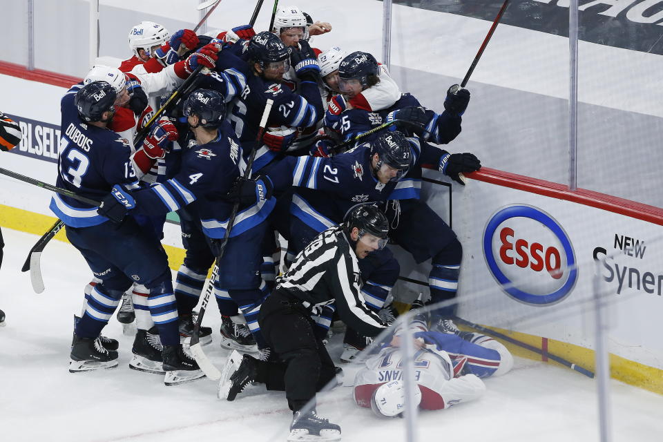 Montreal Canadiens' Jake Evans (71) is protected as he lies motionless on the ice after getting hit by Winnipeg Jets' Mark Scheifele (55) during the third period of Game 1 of an NHL hockey Stanley Cup second-round playoff series Wednesday, June 2, 2021, in Winnipeg, Manitoba. (John Woods/The Canadian Press via AP)