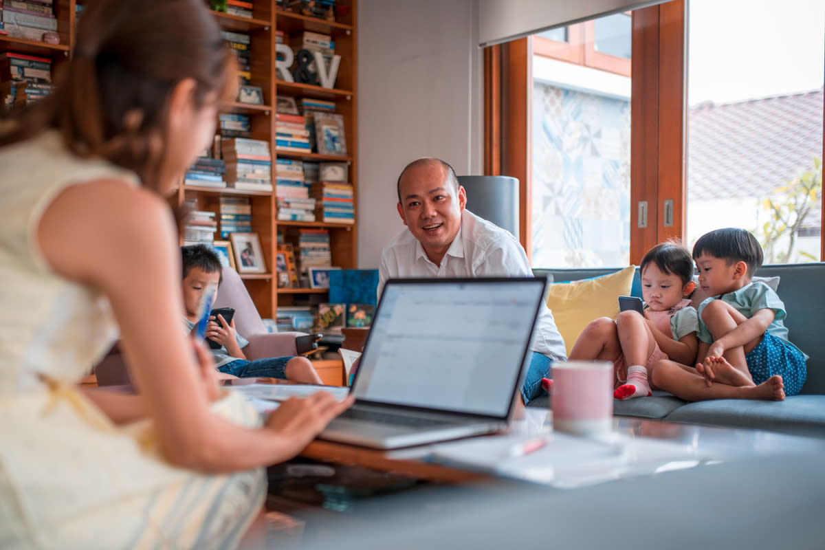 A woman works from home as her husband entertains their children. 