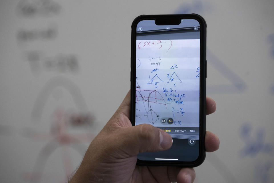 A student uses his phone to copy the whiteboard at the end of a summer math boot camp session on Thursday, Aug. 1, 2023 at George Mason University in Fairfax. Va. (AP Photo/Kevin Wolf)