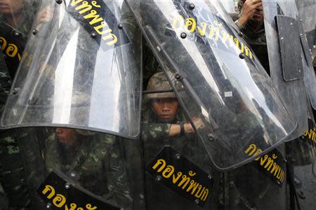 A soldier looks out from behind shields as they take up position to block protestors at a shopping district in central Bangkok May 25, 2014. REUTERS/Erik De Castro