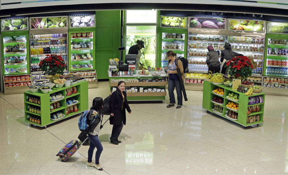 In this photo taken Tuesday, Dec. 18, 2012, at O'Hare International Airport in Chicago, travelers visit O'Hare Urban Garden farmers market in Terminal 2. Getting stranded at an airport once meant camping on the floor and enduring hours of boredom in a kind of travel purgatory with nothing to eat but fast food. Tough economic times are helping drive airports to make amends and transform terminals with a bit of bliss: spas, yoga studios, luxury shopping and restaurant menus crafted by celebrity chefs. (AP Photo/M. Spencer Green)