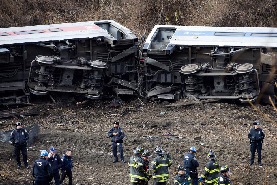 Emergency personnel respond to the scene of a Metro-North passenger train derailment in the Bronx borough of New York Sunday, Dec. 1, 2013. The train derailed on a curved section of track in the Bronx on Sunday morning, coming to rest just inches from the water and causing multiple fatalities and dozens of injuries, authorities said. Metropolitan Transportation Authority police say the train derailed near the Spuyten Duyvil station. (John Minchillo/AP)