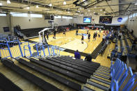 Yeshiva University players, foreground, warm up in a mostly empty Goldfarb Gymnasium at Johns Hopkins University before playing against Worcester Polytechnic Institute in a first-round game at the men's Division III NCAA college basketball tournament, Friday, March 6, 2020, in Baltimore, The university held the tournament without spectators after cases of COVID-19 were confirmed in Maryland. (AP Photo/Terrance Williams)