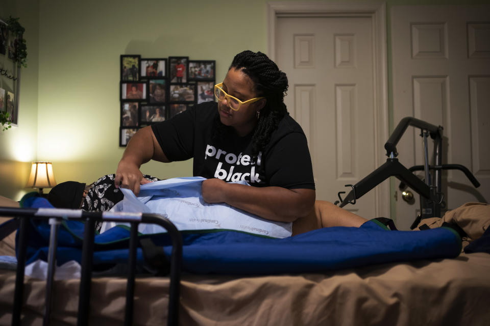 Jessica Guthrie shifts her mother, Constance, onto a harness to move her to the living room in Fredericksburg, Va., on Monday, Sept. 19, 2022. In 2018, her mother started pointing at her stomach, repeatedly, trying to tell her daughter she was in pain, Jessica took her to her primary care physician, who is white, at the time who brushed the concerns aside. Jessica took her mother to the emergency room the next day and a Black male doctor ordered the necessary imaging. She needed emergency surgery to correct a painful, protruding hernia. (AP Photo/Wong Maye-E)