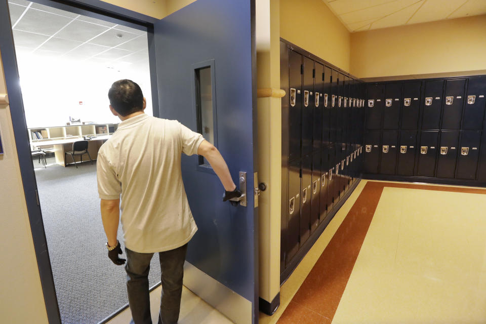 A school janitor opens the door to a staff room inside Bothell High School, closed for the day, Thursday, Feb. 27, 2020, in Bothell, Wash. The suburban Seattle school was closed Thursday after a staffer's family member was placed in quarantine for showing symptoms of possibly contracting the new virus that started in China - an action health officials say is unnecessary. The school will be cleaned and disinfected while students stay home. (AP Photo/Elaine Thompson)