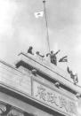 FILE - In this December, 1937, file photo, Japanese soldiers cheer as they hoist their flag from the roof of the central government building after they seized Nanking in the Second Sino Japanese War. China and an international postwar tribunal said at least 200,000 civilians were killed by Japanese troops in a weekslong frenzy of murder, rape and arson after Nanking, then China's capital, fell to Japan on Dec. 13, 1937. (AP Photo, File)