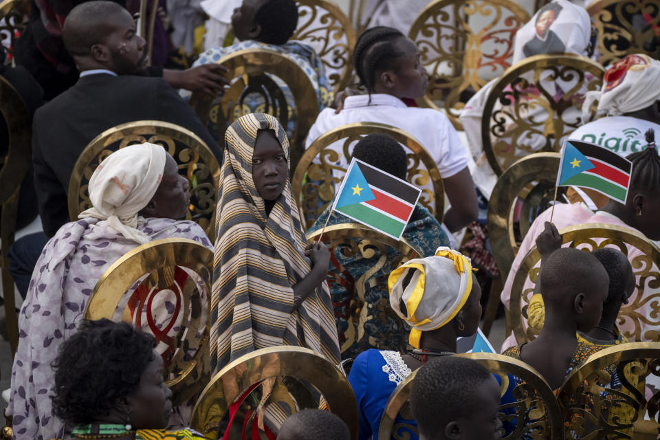 A girl holds a national flag as she and others await the arrival of Pope Francis for a Holy Mass at the John Garang Mausoleum in Juba, South Sudan Sunday, Feb. 5, 2023. Pope Francis is in South Sudan on the final day of a six-day trip that started in Congo, hoping to bring comfort and encouragement to two countries that have been riven by poverty, conflicts and what he calls a "colonialist mentality" that has exploited Africa for centuries. (AP Photo/Ben Curtis)