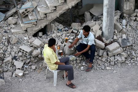 A worker (R) of Adaleh Foundation breaks his fast amidst damaged buildings during the holy month of Ramadan in the rebel-held besieged town of Douma to the east of Damascus, Syria, June 18, 2017. REUTERS/Bassam Khabieh SEARCH "IFTAR ADALEH" FOR THIS STORY. SEARCH "WIDER IMAGE" FOR ALL STORIES.