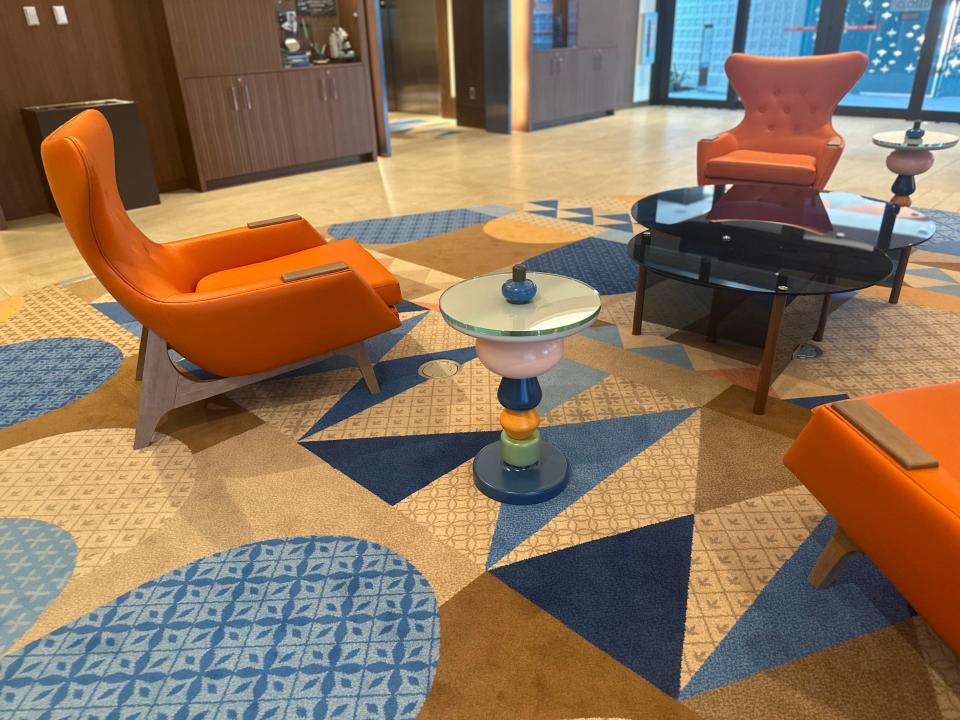 Mid-century modern orange chairs on top of patterned carpet in hotel lobby