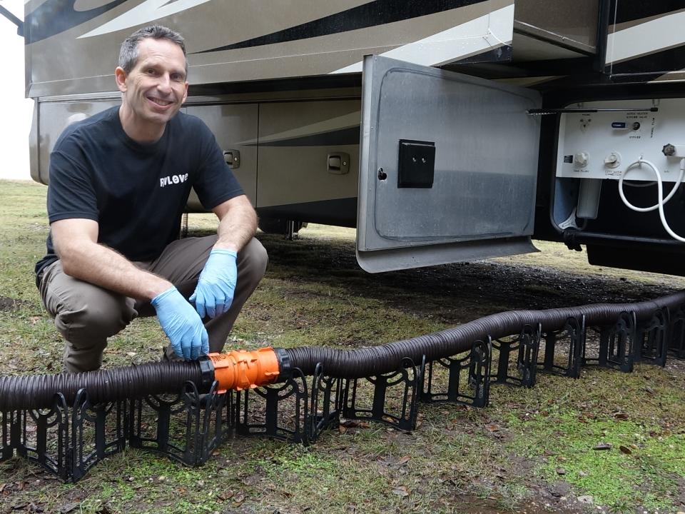 Marc squats behind the RhinoFLEX sewer hose with gloves on.