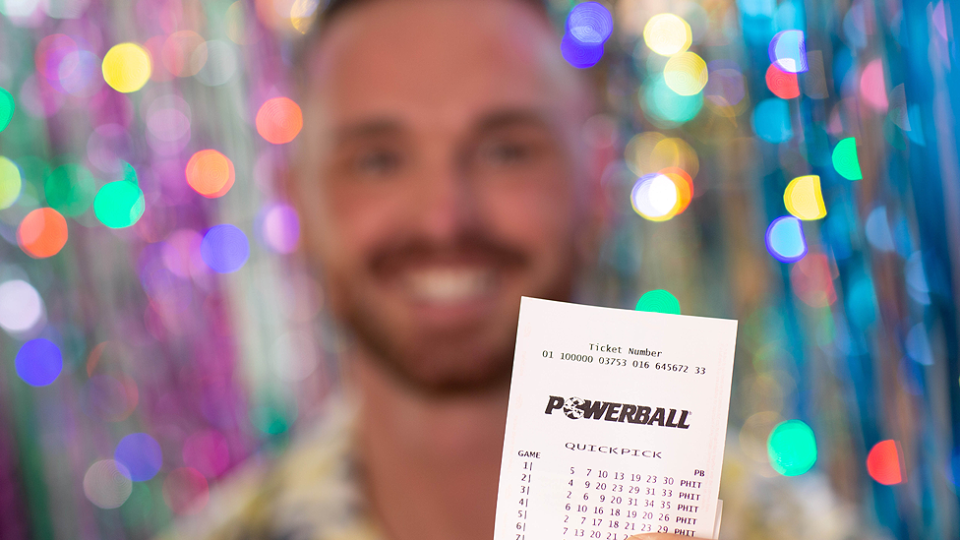 A man is pictured holding a Powerball ticket.