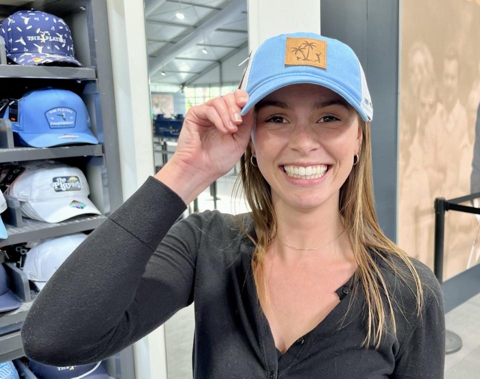 Annie Clemens, a member of the PGA Tour merchandise staff, models the hat she designed for sale at the PGA Tour Fan Shop during the week of the 2023 Players Championship.