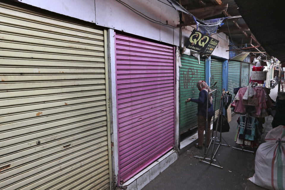 In this Thursday, April 30, 2020, photo, a woman closes her shop after collecting some leftover items at Tanah Abang textile market that is closed due to the new coronavirus outbreak in Jakarta, Indonesia. May Day usually brings both protest rallies and celebrations rallies marking international Labor Day. This year it's a bitter reminder of how much has been lost for the millions left idle or thrown out of work due to the coronavirus pandemic. Garment workers in Asia are among the hardest hit as orders dry up and shutdowns leave factories shuttered. (AP Photo/Tatan Syuflana)