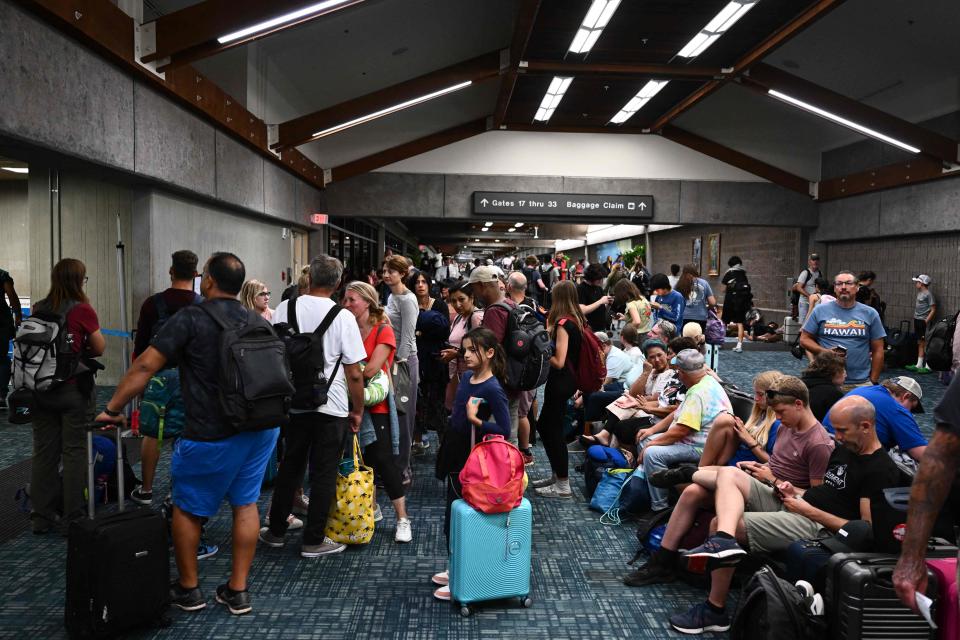 Passengers try to rest after canceled and delayed flights as thousands were stranded at the Kahului Airport in the aftermath of wildfires in western Maui on Aug. 9, 2023.