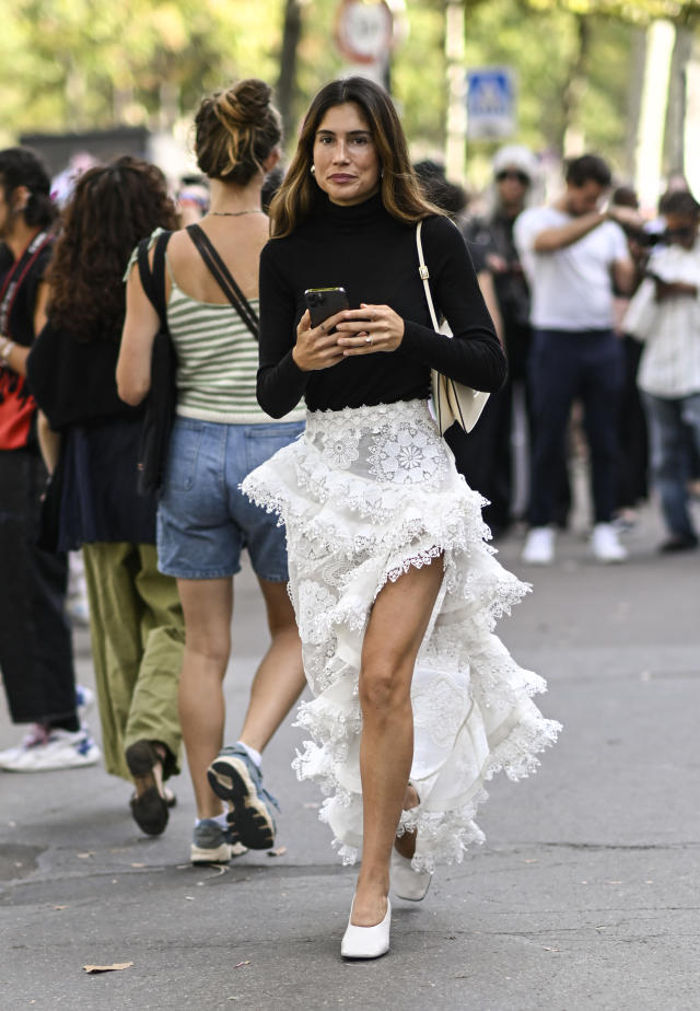 A guest wearing white top and skirt and Louis Vuitton bag outside