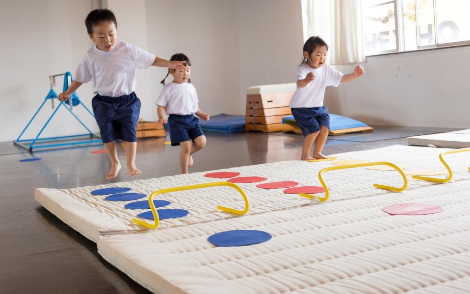 Japanese children practicing mat exercise and horizontal bar