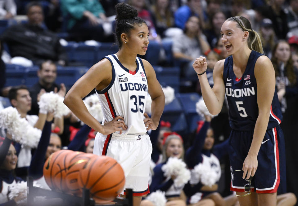 FILE - Connecticut's Paige Bueckers, right, talks with teammate Azzi Fudd, left, as Fudd participates in a 3-point contest during First Night events for the school's men's and women's NCAA college basketball teams Oct. 14, 2022, in Storrs, Conn. Bueckers, the national player of the year as a freshman and a pre-season All-American this year, missed all of last season and most of the previous one with two separate knee injuries. Fudd has also had injuries that put her on the bench for significant portions of both her freshman and sophomore seasons at UConn. (AP Photo/Jessica Hill, File)