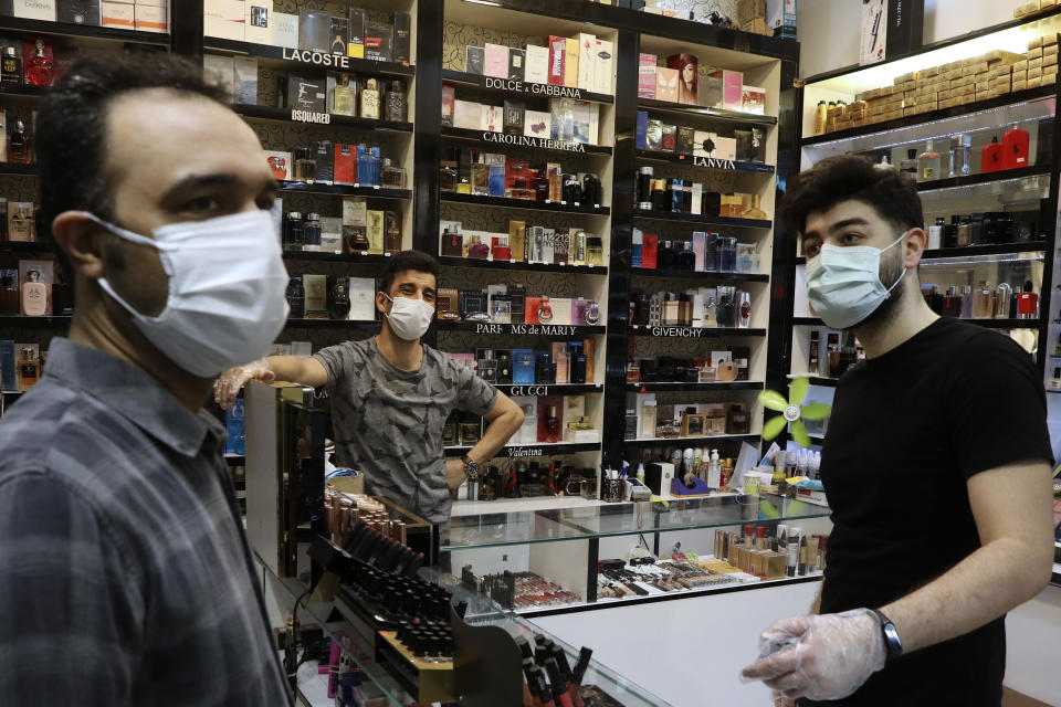 Shopkeepers wear protective face masks and gloves to help prevent the spread of the coronavirus in a perfume and cosmetics shop at the Kourosh Shopping Center in Tehran, Iran, Monday, April 20, 2020. Iran on Monday began opening intercity highways and major shopping centers to stimulate its sanctions-choked economy, gambling that it has brought under control its coronavirus outbreak — one of the worst in the world — even as some fear it could lead to a second wave of infections. (AP Photo/Vahid Salemi)