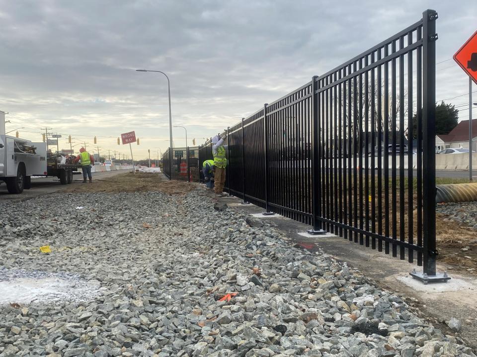 Construction crews work on a recently installed fence along Route 13 near Third Avenue in the New Castle area on Dec. 22, 2023. This is part of the Routes 13/40 Memorial Drive pedestrian improvements project.