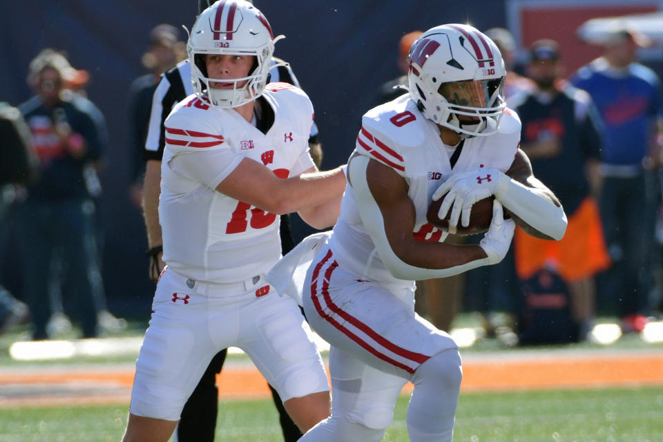 Oct 21, 2023; Champaign, Illinois, USA; Wisconsin Badgers quarterback Braedyn Locke (18) hands the ball to running back Braelon Allen (0) against the Illinois Fighting Illini during the first half at Memorial Stadium. Mandatory Credit: Ron Johnson-USA TODAY Sports