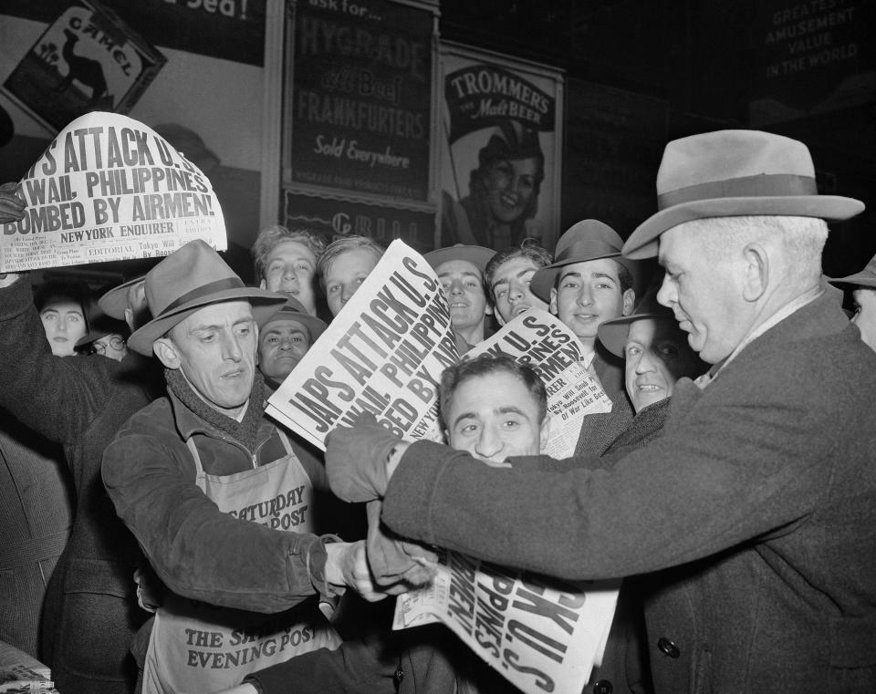 In this Dec. 7, 1941 file photo, people buy newspapers reporting the Japanese attack on U.S. bases in the Pacific Ocean, at Times Square in New York.