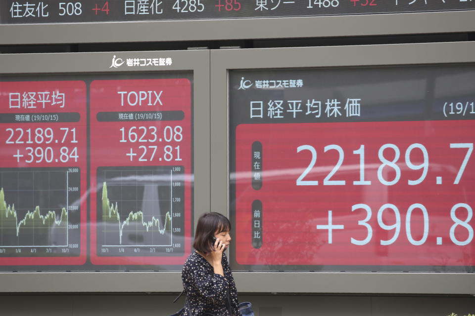 A woman walks by an electronic stock board of a securities firm in Tokyo, Tuesday, Oct. 15, 2019. On Tuesday, shares are mixed in Asia after a wobbly day of trading on Wall Street. Japan’s Nikkei 225 index jumped 1.8% as it reopened from a public holiday and investors caught up on the news of a preliminary trade deal between China and the U.S. (AP Photo/Koji Sasahara)