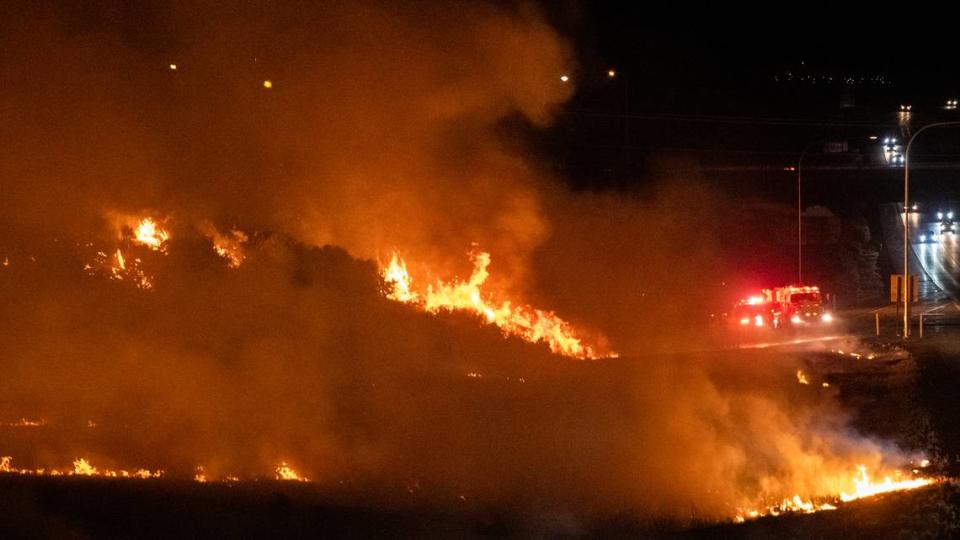 A brush fire that appeared to start in multiple places along Interstate 182 in south Richland threatened nearby homes and buildings.