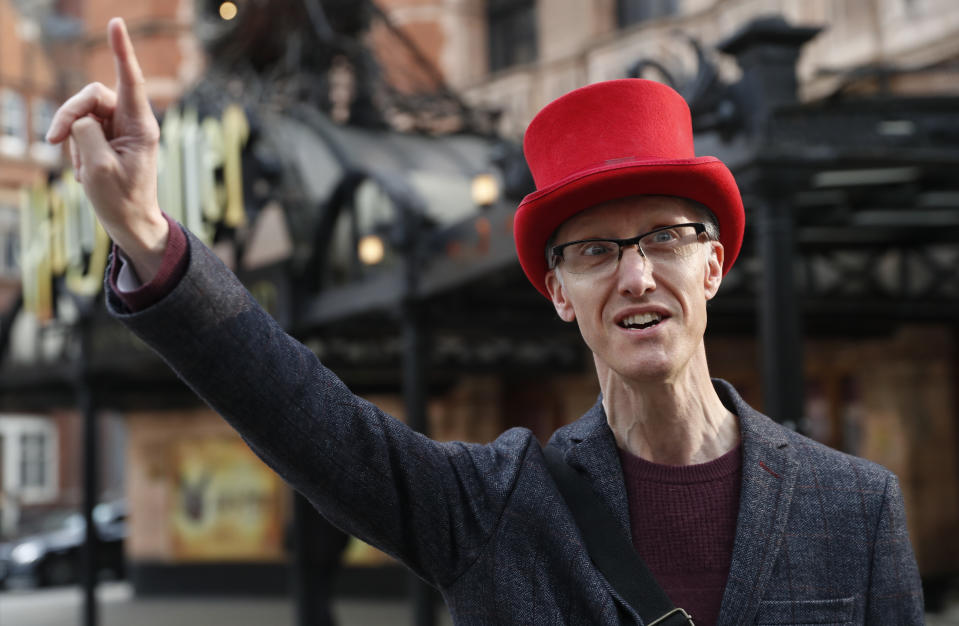 Neil Maxfield who runs a theater walking tour that takes about two hours and visits some 14 London theaters gestures during an interview with the Associated Press outside the Palace Theater in London, Tuesday, April 20, 2021. One of those sidelined when the pandemic forced theaters to close was Neil Maxfield, who turned his love of musicals into a job leading walking tours of London's West End, the district that is home to more than three dozen theaters and long-running juggernaut shows including "Les Miserables," "The Lion King," "Hamilton" and "Harry Potter and the Cursed Child." (AP Photo/Alastair Grant)