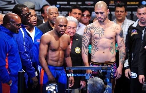 US boxer Floyd Mayweather (L) and Puerto Rico's Miguel Cotto eye the scale during Cotto's weigh-in on May 4, in Las Vegas, Nevada, on the eve of their Super Welterweight championship fight