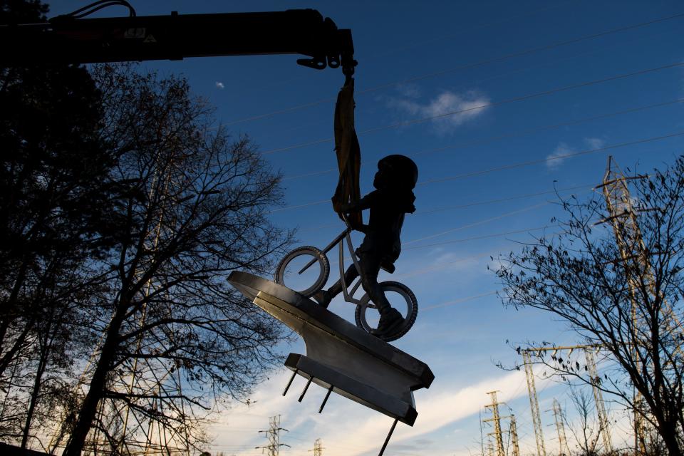 Workers install a statue of a young bicyclist along the Swamp Rabbit Trail near San Souci Tuesday, Dec. 3, 2019. The statue was created by Charles Pate Jr. and Ryan Calloway and was commissioned by Bike Walk Greenville.