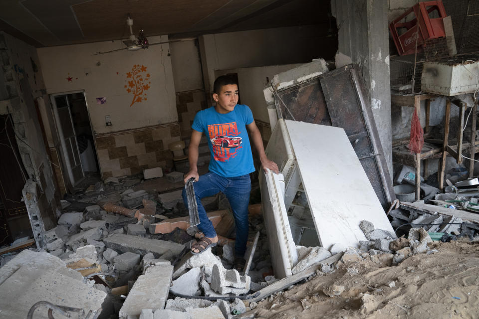 A child stands inside a severely damaged building neighboring the crater where the home of Ramez al-Masri was destroyed by an air-strike prior to a cease-fire reached after an 11-day war between Gaza's Hamas rulers and Israel, Sunday, May 23, 2021, in Beit Hanoun, the northern Gaza Strip. (AP Photo/John Minchillo)