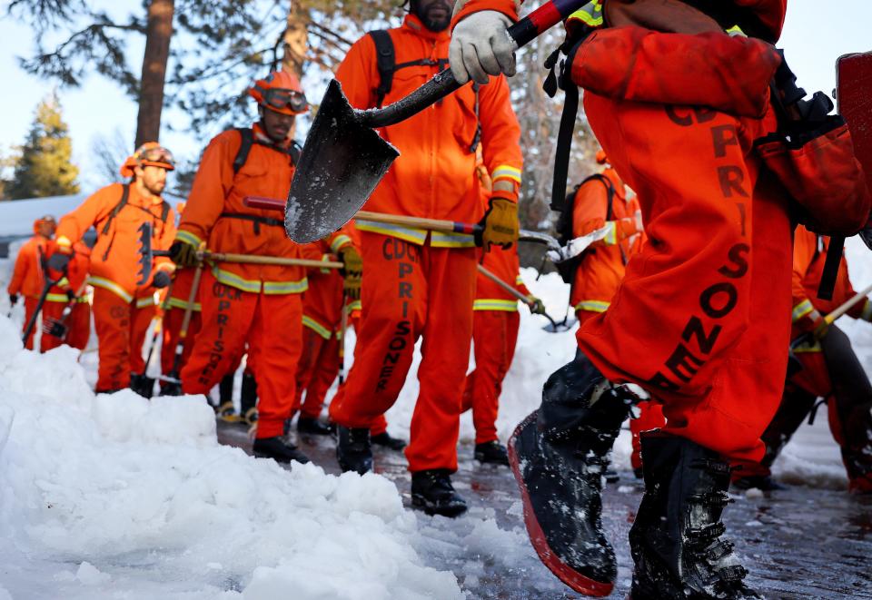 A crew of inmate firefighters walk back to their vehicle after shoveling and clearing snow after a series of winter storms in the San Bernardino Mountains in Southern California on March 3, 2023 in Crestline, California.