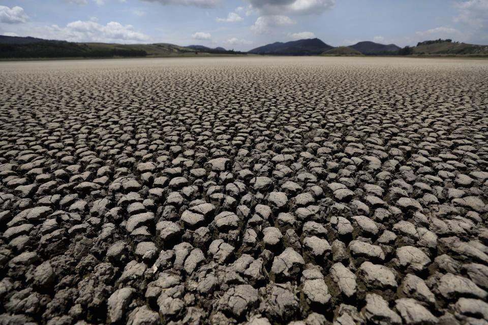 After years of very little rainfall, the lakebed of Suesca lagoon sits dry and cracked, in Suesca, Colombia, Wednesday, Feb. 17, 2021. The basin which is dependent on runoff has suffered severe deforestation and erosion, which together with the added impact of climate change has led to a significant reduction of its water level. (AP Photo/Fernando Vergara)