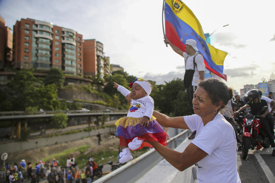 Una seguidora del candidato presidencial Edmundo González sostiene a un bebé mientras espera a que pasen González y la líder opositora María Corina Machado, durante el acto de cierre de campaña en Caracas, Venezuela, el 25 de julio de 2024. (AP Foto/Cristian Hernandez)