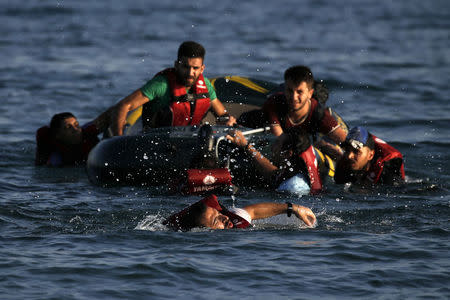 A Syrian refugee swims towards a beach as others are seen on a dinghy whose engine broke down a few hundred meters from the shore of the Greek island of Kos after crossing over from Turkey, August 17, 2015. REUTERS/Alkis Konstantinidis